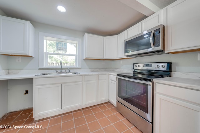 kitchen with light tile patterned flooring, appliances with stainless steel finishes, white cabinetry, and sink