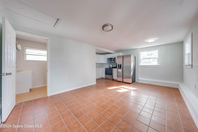 basement with light tile patterned flooring and stainless steel refrigerator with ice dispenser