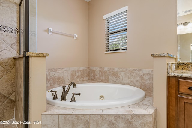 bathroom with tiled tub and vanity