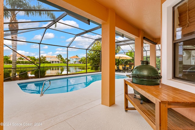 view of swimming pool featuring a patio, a water view, and glass enclosure