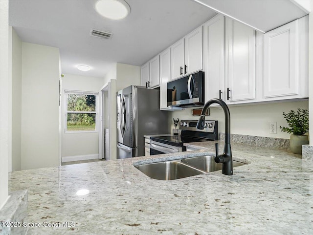 kitchen with sink, light stone countertops, white cabinetry, and stainless steel appliances