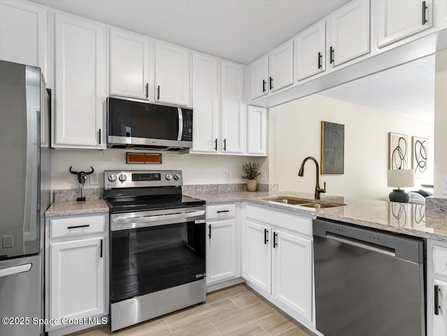 kitchen with light stone countertops, sink, white cabinets, and appliances with stainless steel finishes