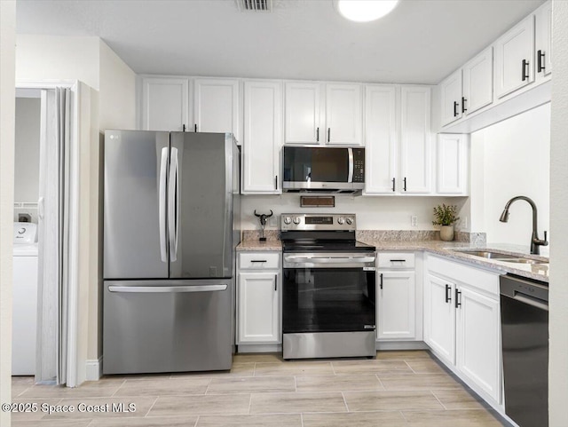 kitchen with light stone countertops, stainless steel appliances, white cabinetry, and sink