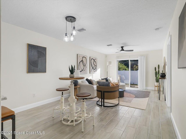 living room featuring ceiling fan and a textured ceiling