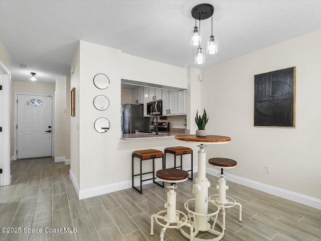 kitchen with sink, kitchen peninsula, decorative light fixtures, a textured ceiling, and appliances with stainless steel finishes