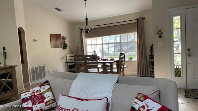 living room featuring lofted ceiling, plenty of natural light, a notable chandelier, and light tile patterned flooring