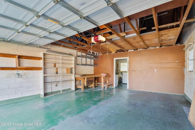 garage featuring a workshop area, a garage door opener, and washer / dryer