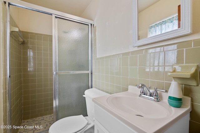 bathroom featuring vanity, toilet, tile walls, and walk in shower