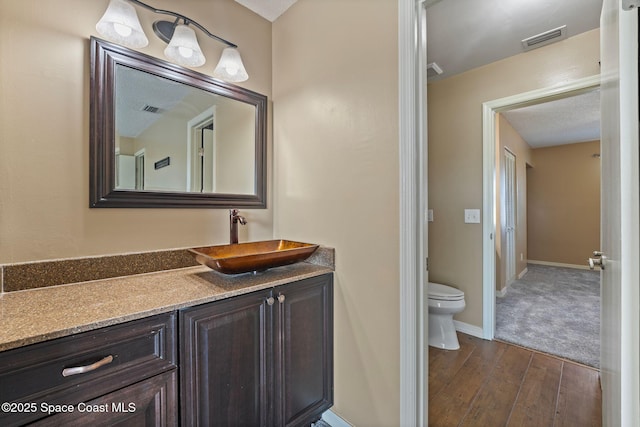 bathroom with vanity, hardwood / wood-style flooring, and toilet