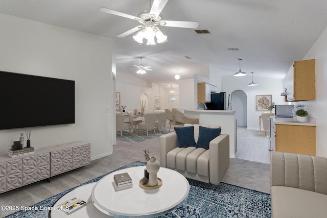 living room with a textured ceiling, ceiling fan, lofted ceiling, and light carpet