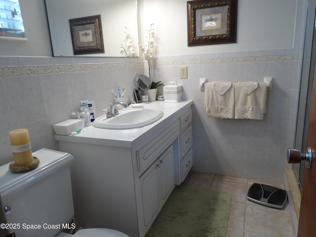 bathroom with tile patterned flooring, vanity, toilet, and tile walls