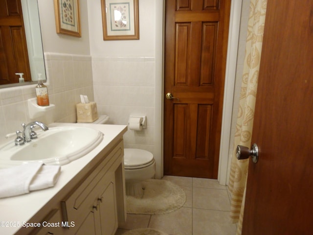 bathroom with tile patterned flooring, vanity, toilet, and tile walls