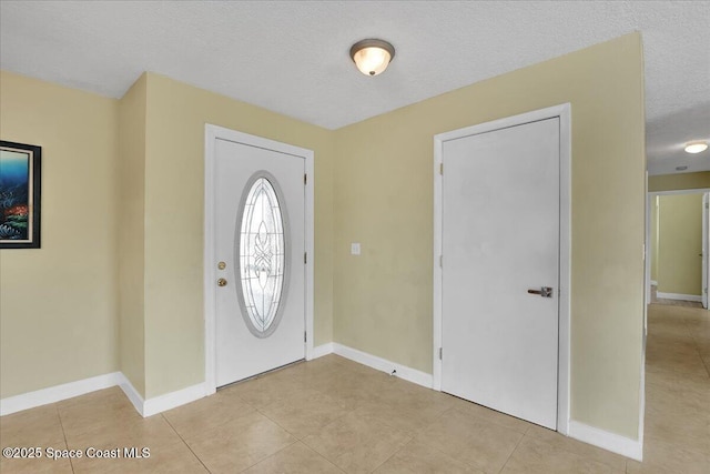 entryway with light tile patterned flooring and a textured ceiling