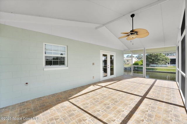 unfurnished sunroom with lofted ceiling with beams, ceiling fan, a water view, and french doors