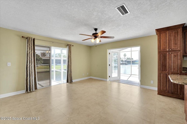 unfurnished room featuring ceiling fan, a water view, and a textured ceiling