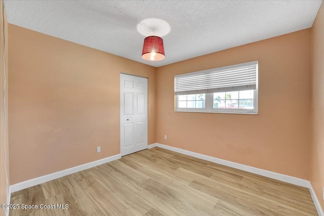 spare room with light hardwood / wood-style floors and a textured ceiling