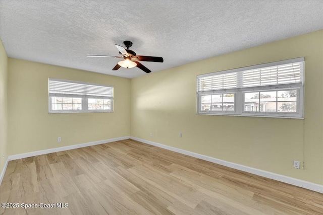 empty room featuring ceiling fan, plenty of natural light, light hardwood / wood-style floors, and a textured ceiling