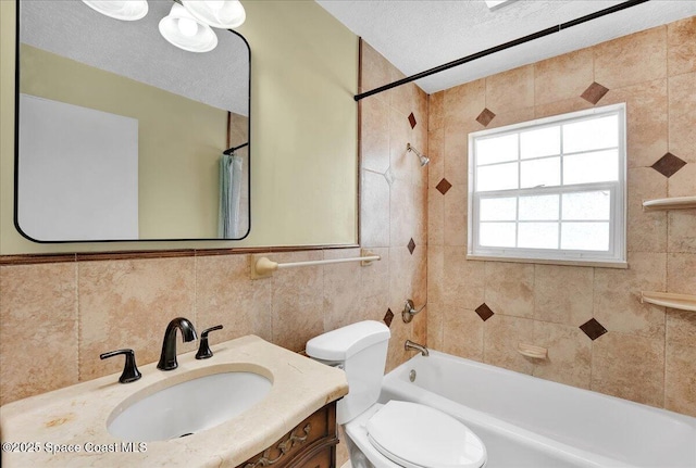 full bathroom with a textured ceiling, tiled shower / bath combo, toilet, and tile walls