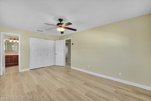 unfurnished bedroom with ceiling fan, light hardwood / wood-style floors, ensuite bathroom, and a closet