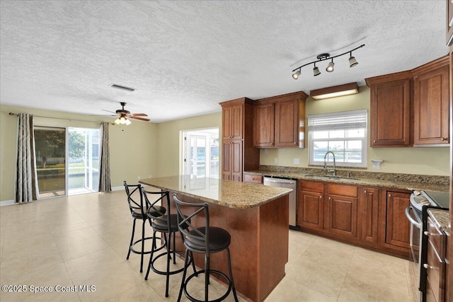 kitchen with a center island, track lighting, sink, ceiling fan, and stainless steel appliances