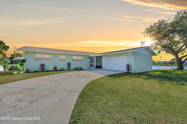 ranch-style home featuring a yard, a water view, and a garage