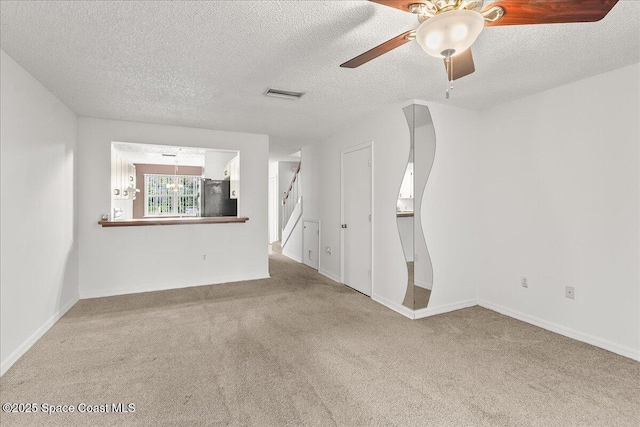 unfurnished living room featuring light carpet, ceiling fan, and a textured ceiling