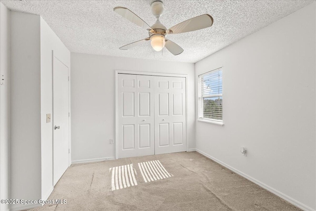 unfurnished bedroom featuring ceiling fan, light colored carpet, a textured ceiling, and a closet