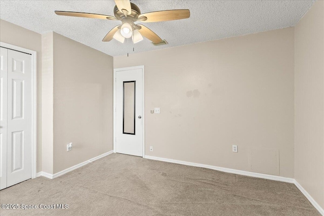 carpeted spare room featuring a textured ceiling and ceiling fan