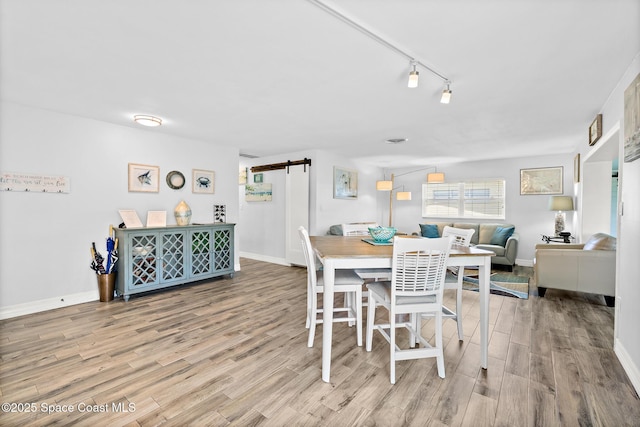 346 Cyprus Dr, Cocoa Beach, FL 32931 - dining room featuring a barn door, wood finished floors, and rail lighting