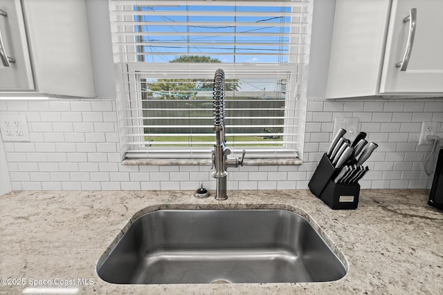346 Cyprus Dr, Cocoa Beach, FL 32931 - kitchen view of decorative backsplash, white cabinetry, and light stone counters