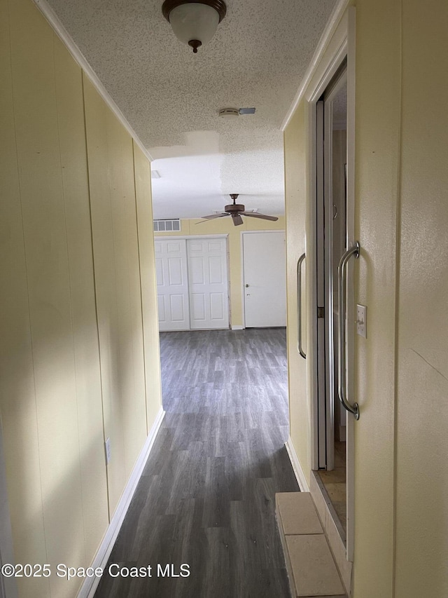 hall with a textured ceiling and dark wood-type flooring