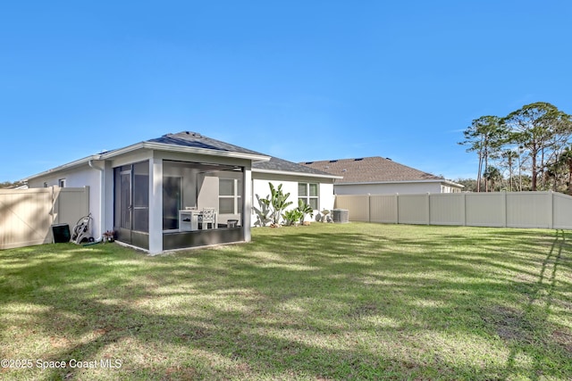 rear view of property featuring central AC unit, a lawn, and a sunroom