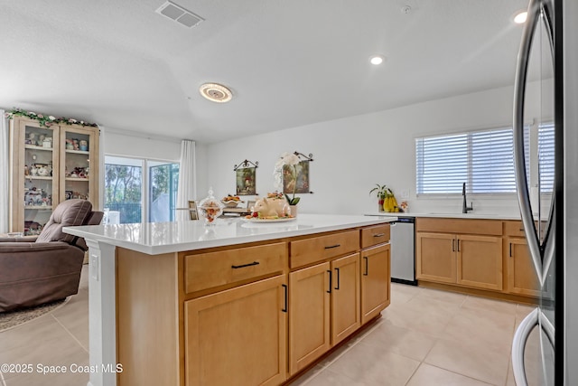 kitchen with sink, light tile patterned flooring, a textured ceiling, a kitchen island, and appliances with stainless steel finishes