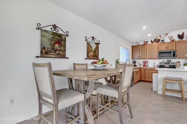 dining area with light tile patterned floors and vaulted ceiling