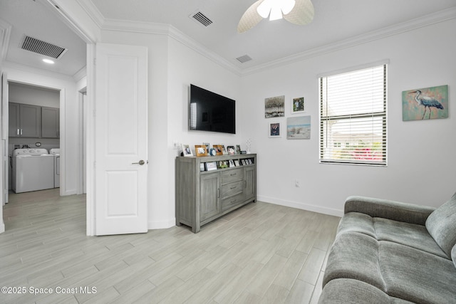 living room featuring ceiling fan, washer and clothes dryer, light wood-type flooring, and ornamental molding