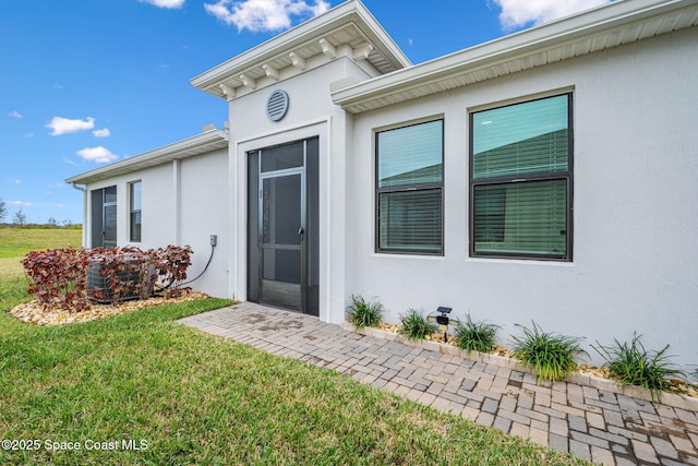 doorway to property featuring a lawn and cooling unit