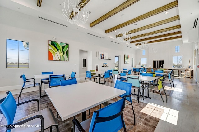 dining room featuring a towering ceiling, plenty of natural light, and beamed ceiling