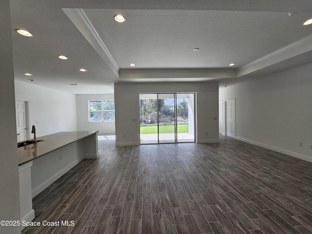 unfurnished living room featuring a textured ceiling, dark hardwood / wood-style flooring, and a raised ceiling