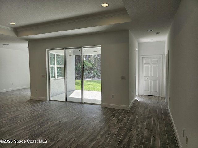 unfurnished room featuring dark hardwood / wood-style flooring, ornamental molding, a raised ceiling, and a textured ceiling