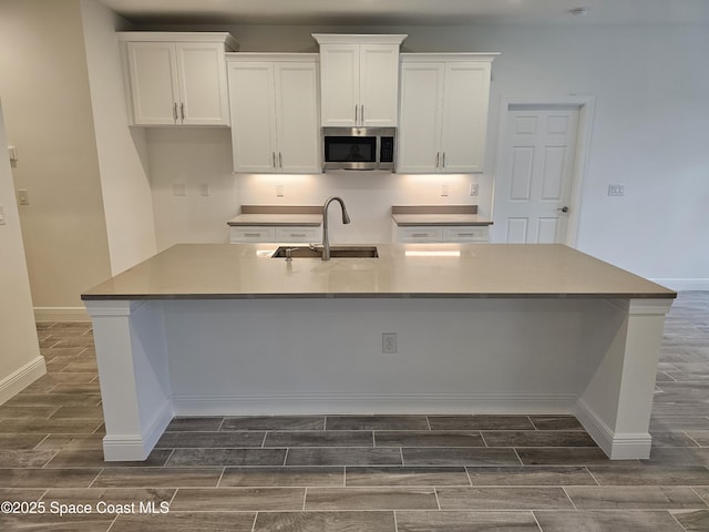 kitchen with sink, white cabinetry, and a kitchen island with sink