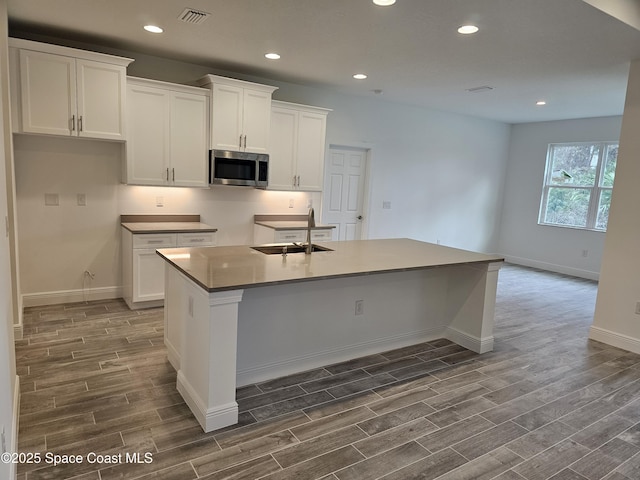 kitchen featuring a center island with sink, white cabinetry, and sink