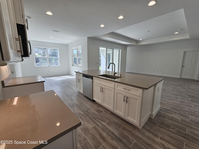 kitchen featuring sink, white cabinetry, a tray ceiling, dishwasher, and a kitchen island with sink