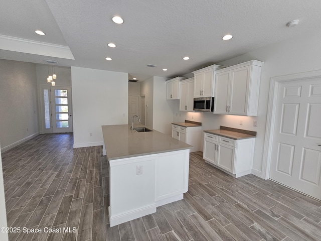 kitchen with sink, a kitchen island with sink, white cabinetry, and a textured ceiling