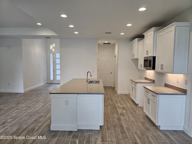 kitchen with sink, a kitchen island with sink, and white cabinetry