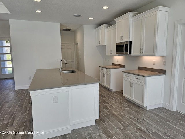 kitchen featuring sink, an island with sink, and white cabinets