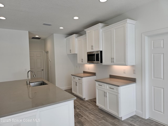 kitchen with sink, a textured ceiling, and white cabinets