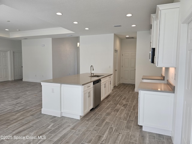 kitchen with white cabinetry, a kitchen island with sink, sink, a tray ceiling, and appliances with stainless steel finishes