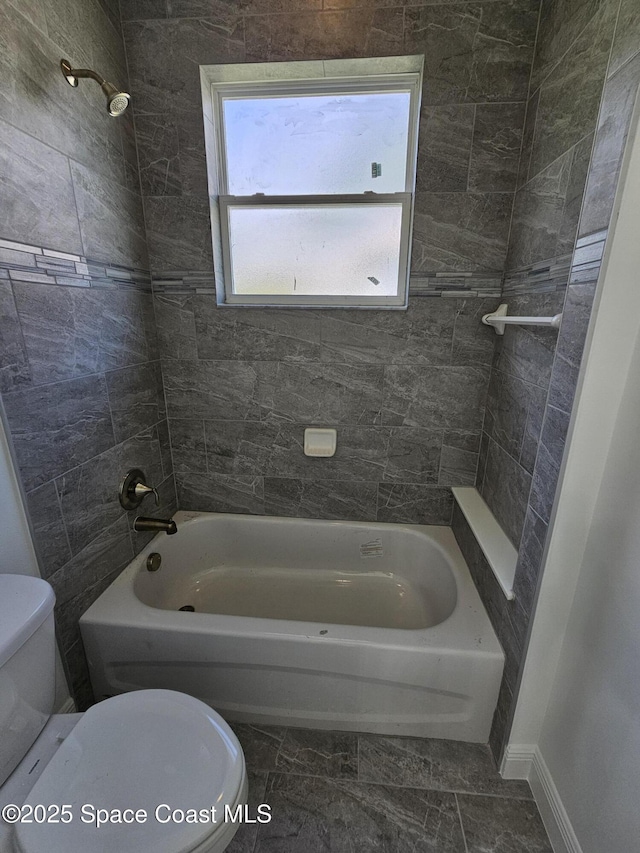 bathroom featuring tiled shower / bath combo and toilet