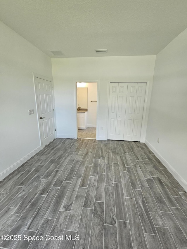 unfurnished bedroom with a closet and ensuite bathroom