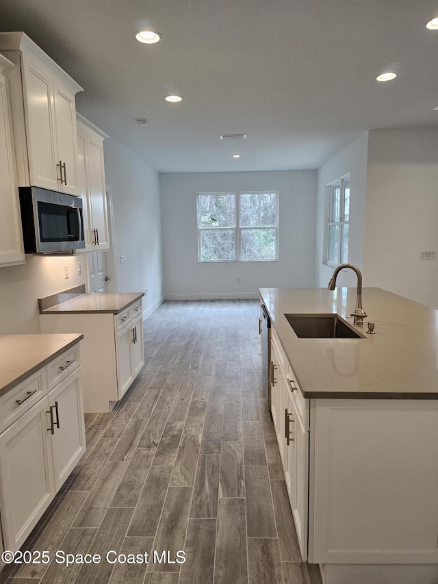 kitchen with sink, stainless steel appliances, an island with sink, and white cabinets